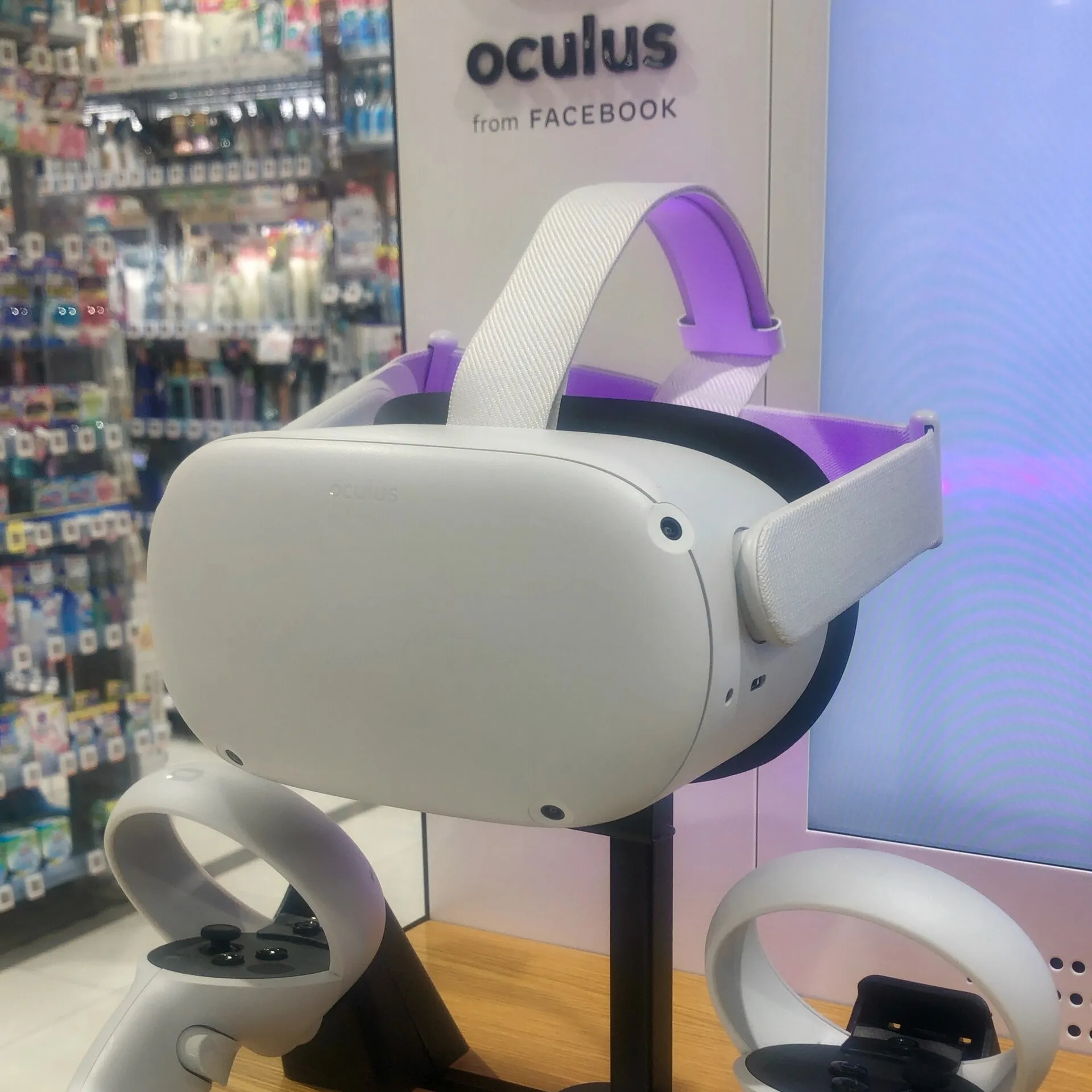 A white Oculus Quest 2 headset and its two controllers on a store display stand